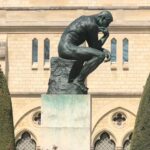 The iconic Thinker statue in Paris in front of a historic building.