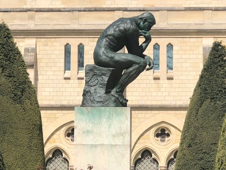 The iconic Thinker statue in Paris in front of a historic building.